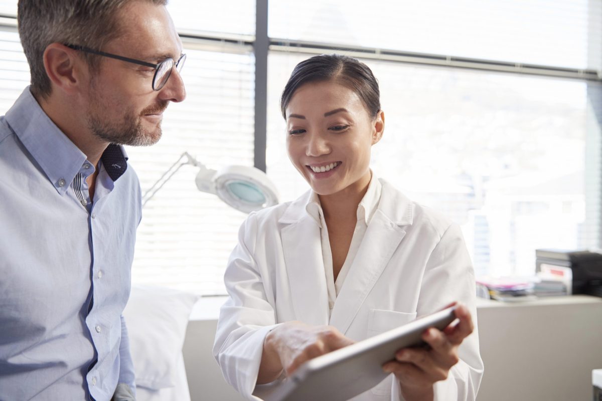 Advanced Primary Care Management (APCM) doctor discussing care plan with patient using tablet.