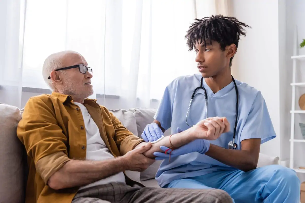 Community Health Integration (CHI) nurse checking elderly patient’s pulse during in-home healthcare visit.