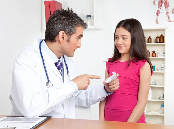 Pediatrician educating young patient on inhaler usage for remote respiratory monitoring under CPT 98976, illustrating patient engagement in digital asthma care.