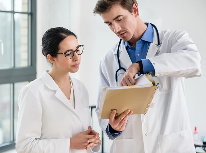 Two physicians reviewing patient chart together, highlighting clinical collaboration, case review, and team-based care coordination in medical practice