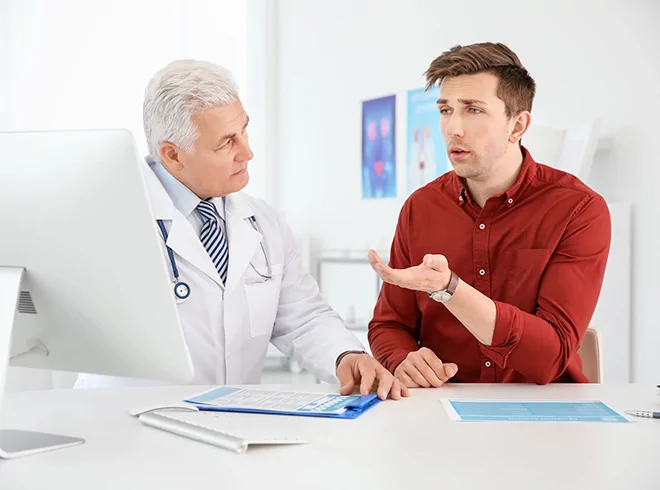 Middle-aged male patient consulting with senior doctor in modern clinic, representing patient engagement and preventative health discussions in primary care