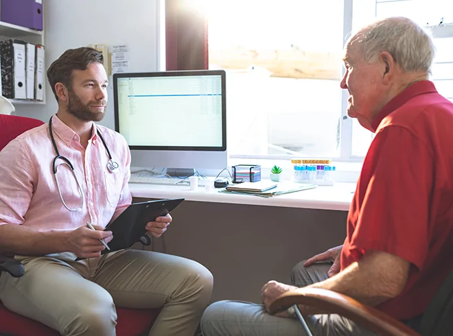 Primary care doctor discussing health concerns with senior male patient in modern clinic, highlighting patient engagement and care planning for chronic conditions