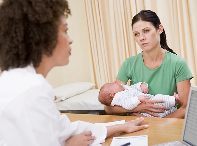Concerned mother holding newborn during consultation with healthcare provider, illustrating postpartum depression screening, maternal mental health support, and early intervention care